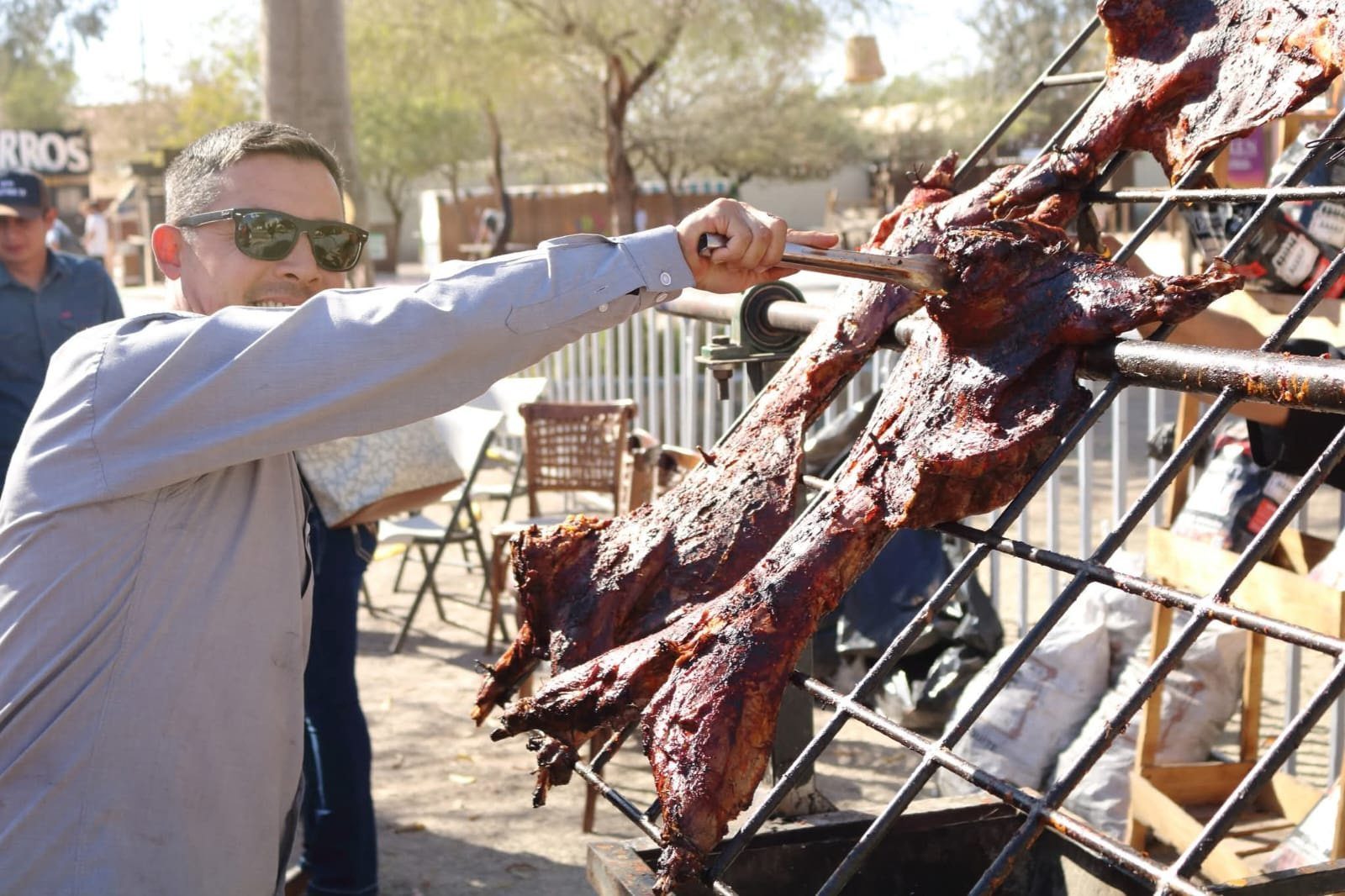 Parrillero volteando un costillar sobre la parrilla