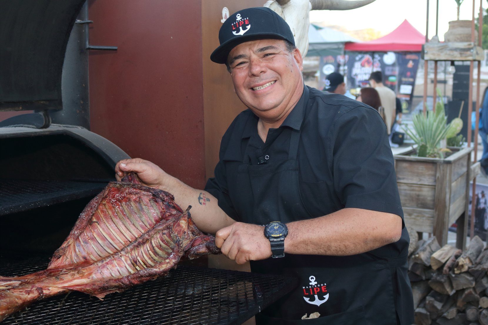 Parrillero sosteniendo un corte grande frente al asador